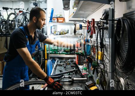 Bicycle repair in workshop, man takes tools Stock Photo