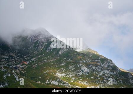 alpine landscape - the tops of the peaks are hidden by clouds through which the sun shines Stock Photo