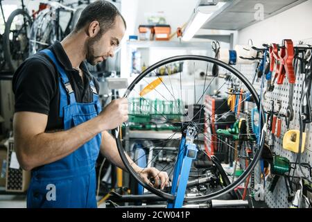 Bicycle repair in workshop, man works with wheel Stock Photo