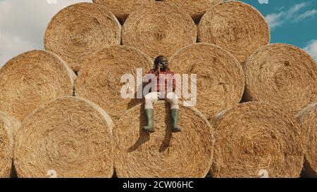 African black farmer sitting on the haystack and having a phone call. High quality photo Stock Photo
