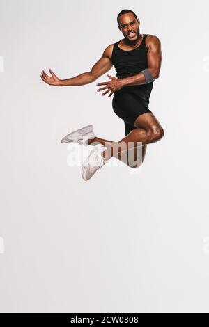 African american athlete doing fitness exercise. Fit man jumping high in air during workout. Stock Photo