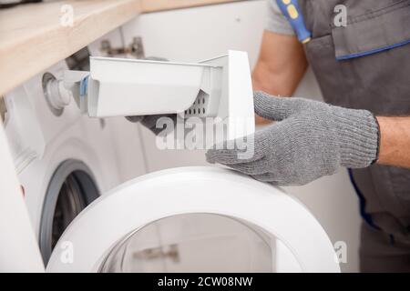 Concept service technician. Working man in medical mask plumber repairs fix washing machine Stock Photo