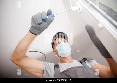 Worker man installs plastic windows and doors with double-glazed white Stock Photo