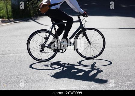 male cyclist in the backlit casting a shadow on the street