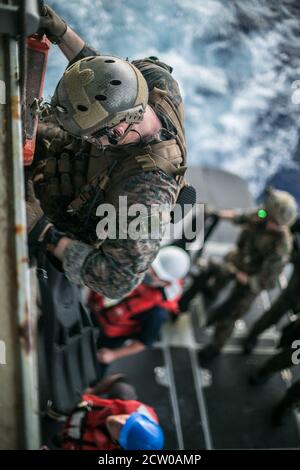 PHILLIPPINE SEA (Sept. 9, 2020) A Marine with the Amphibious Reconnaissance Platoon, 31st Marine Expeditionary Unit (MEU), climbs down a caving ladder to board a rigid-hull inflatable boat from the amphibious assault ship USS America (LHA 6) to conduct a Reconnaissance and Surveillance training mission in preparation for a boat raid. The Amphibious Reconnaissance Platoon specializes in ground and amphibious reconnaissance operations as the primary reconnaissance and surveillance element of the 31st MEU. America, flagship of America Amphibious Ready Group (ARG), 31st MEU team, is operating in t Stock Photo