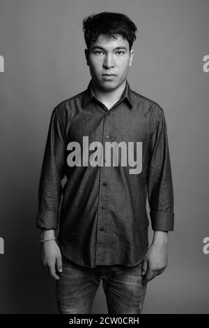 Young Asian man wearing button down shirt against gray background Stock Photo