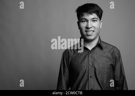 Young Asian man wearing button down shirt against gray background Stock Photo