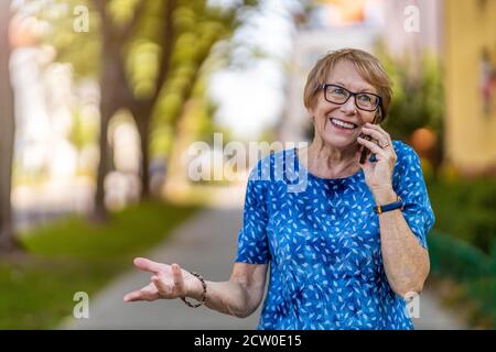 Happy senior woman using mobile phone outdoors Stock Photo