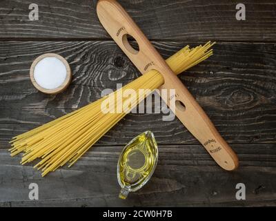 Spaghetti wooden measure, olive oil and salt on wooden table. Overhead shot. Stock Photo