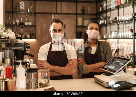 Coffee shop owners with face masks, lockdown, quarantine, coronavirus, back to normal concept Stock Photo