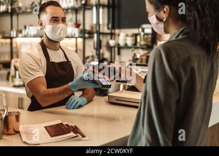 Customer paying and getting her order at the coffee shop counter during quarantine Stock Photo