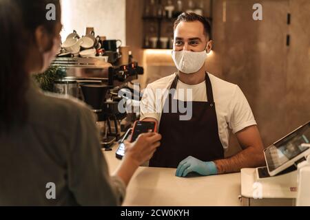 Customer paying and getting her order at the coffee shop counter during quarantine Stock Photo