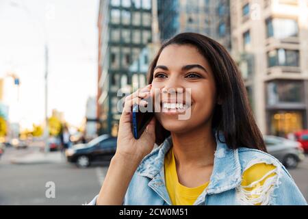 Cheerful young woman making a phone call outdoors in the city Stock Photo