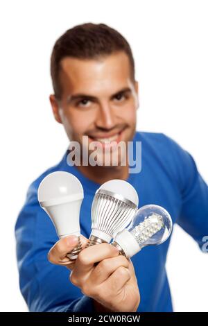 portrait of happy young man, holding three different LED bulbs on white background Stock Photo