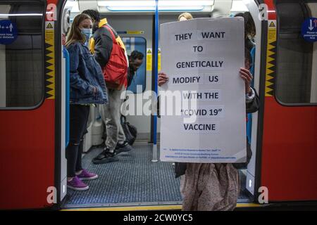 Anti Coronavirus Vaccination protester travels on the London Underground holding a placard, London, UK