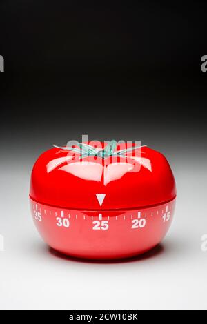 Tomato-shaped kitchen timer set at 25 minutes to fight procrastination in studying and working. Stock Photo