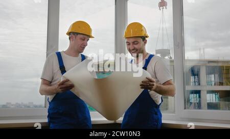 Workers in helmets looking at drawings, repairs Stock Photo