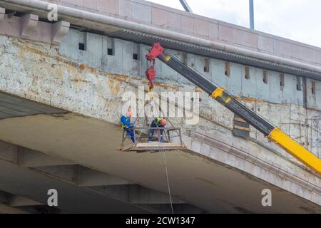 Male workers hanging and doing repairing works for a bridge Stock Photo