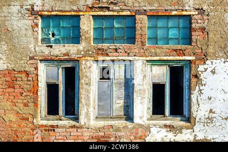Grunge damaged broken windows in brick ruined building wall Stock Photo