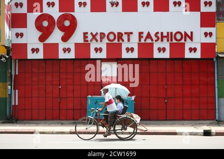 Yangon, Myanmar. 26th Sep, 2020. A trishaw driver wearing a mask rides past a closed clothing store in Yangon, Myanmar, Sept. 26, 2020. The number of COVID-19 infection cases in Myanmar reached 9,991 on Saturday night, said a release from the Health and Sports Ministry. According to the release, Myanmar reported 880 new confirmed cases and 24 more deaths on Saturday night. Credit: U Aung/Xinhua/Alamy Live News Stock Photo