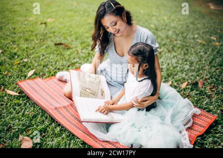 Beauiful young teacher teaching her pupil in the green field. Stock Photo