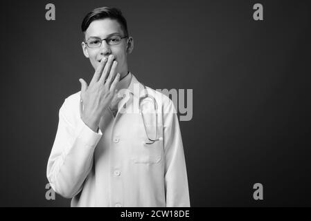 Studio shot of young handsome doctor against gray background Stock Photo