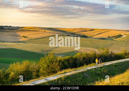 People walking along a chalk path looking at the view from Cissbury Ring in West Sussex, England on a summers evening Stock Photo