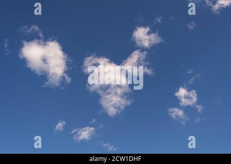 small white fluffy clouds against a blue sky Stock Photo