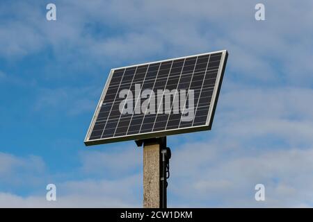 Single solar panel on a post with a blue sky background Stock Photo