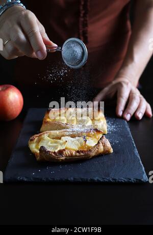 Apple phyllo tart sprinkled with icing sugar on dark background. Stock Photo