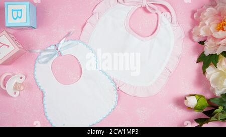 Baby bib nursery clothing mom bloggers desktop mockups with peonie floers on pink textured background. Top view blog hero header creative composition