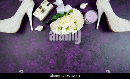 Wedding bridal theme desktop workspace with high heel shoes, bouquets, accessories on vintage purple textured background. Top view blog hero header cr Stock Photo