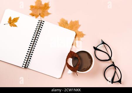 Autumn flat lay with dry leaves, notebook, eyeglasses and coffee cup on pastel beige studio background with copy space for advertisement. Thanksgiving Stock Photo