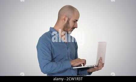 Young middle eastern businessman, standing and typing on laptop Stock Photo
