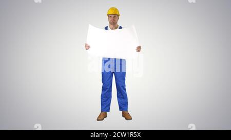 Construction worker checking blueprints on site on gradient back Stock Photo