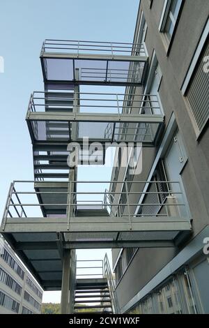 Long set of metal stairs, fire escape route, attached to outside of modern industrial and administrative brick building in Dietikon, Switzerland. Stock Photo