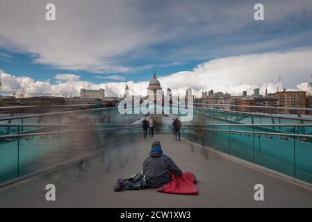 A homeless man with his dog on the Millennium Bridge in London, United Kingdom Stock Photo