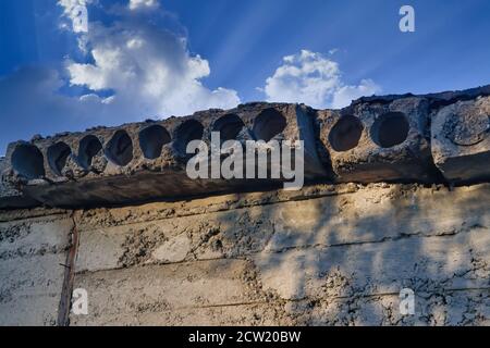 Close up of concrete plates surface. Concrete slabs with holes against the background of blue sky and white clouds. Stock Photo