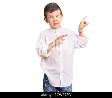 Cute blond kid wearing elegant shirt pointing aside worried and nervous with both hands, concerned and surprised expression Stock Photo