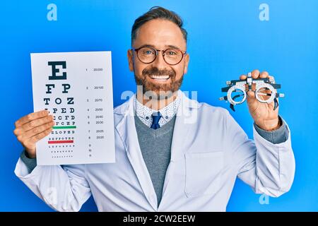 Handsome middle age man holding optometry glasses and medical exam smiling with a happy and cool smile on face. showing teeth. Stock Photo