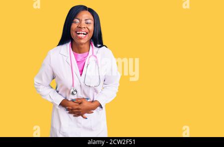 Young african american woman wearing doctor stethoscope smiling and laughing hard out loud because funny crazy joke with hands on body. Stock Photo