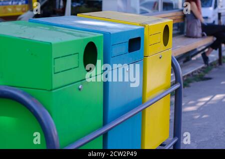 Three multi-colored garbage containers on a city street. Yellow, blue and green rectangular containers for waste separation. Ecological concept. Selec Stock Photo