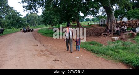 DISTRICT KATNI, INDIA - DECEMBER 15, 2019: Indian village poor Father and Son going on street with holded hand. Stock Photo