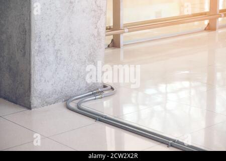 Electric cable pipe or conduit fixing on the concrete floor Construction work. Wiring system installation inside the building. Stock Photo