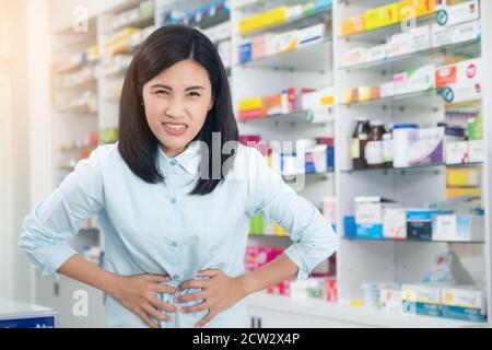 Female patient having stomach pain background  pharmacy. Healthcare and medical concept. Stock Photo