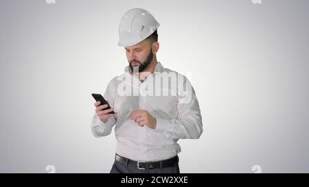 Engineer walking and using smartphone on gradient background. Stock Photo