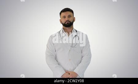 Doctor with a beard looking to camera on gradient background. Stock Photo