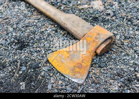 A rusty ax lies on the ground on fine gravel and pebbles Stock Photo