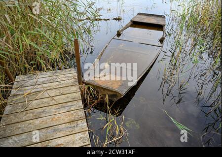 old wooden boat filled with water at jetty Stock Photo