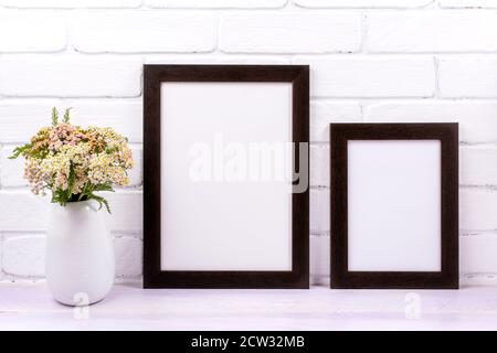 Two black brown frames mockup with pink yarrow wildflowers in the vase. Empty poster frame mock up for presentation design. Template framing for moder Stock Photo